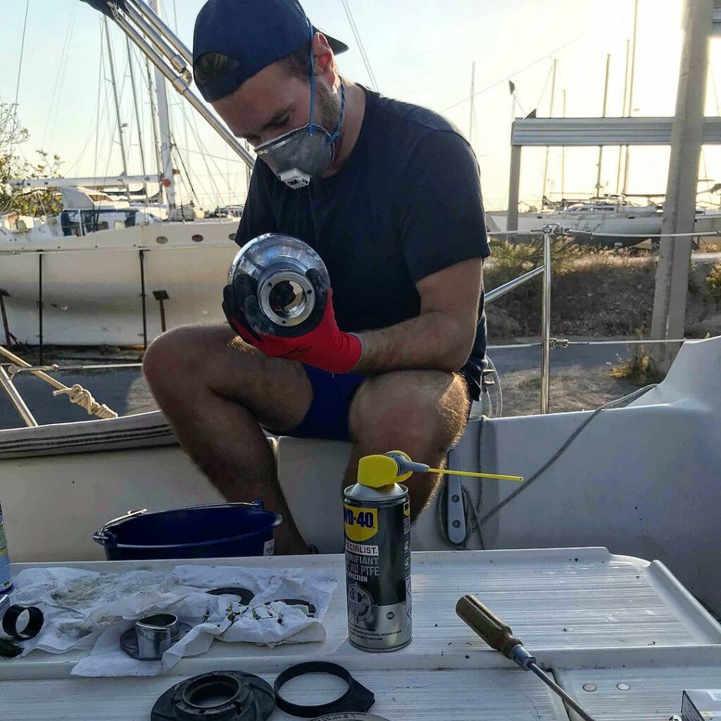 Romain Valverde, masqué, effectue l'entretien d'un des winchs du bateau. Les winchs ont besoin d'un bon nettoyage régulier pour bien fonctionner.