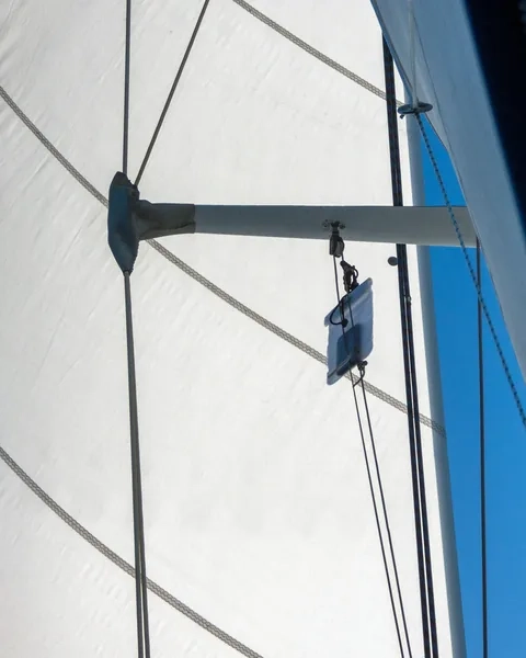 An electronic device in a waterproof pouch is hanging from the rigging of a sailboat under sail