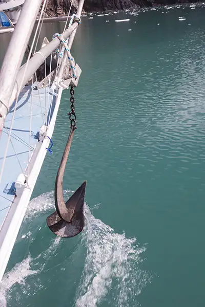 An anchor is dropped at water-level at the bow of a sailing yacht